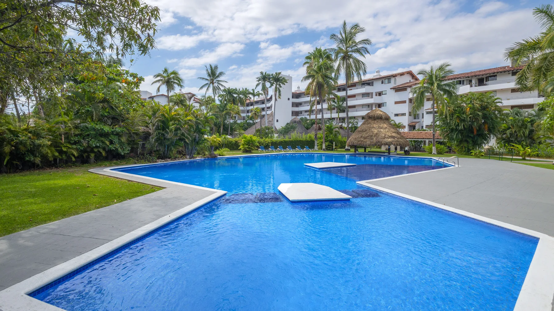 Swimming pool at Marina Las Palmas framed by palms and palapas