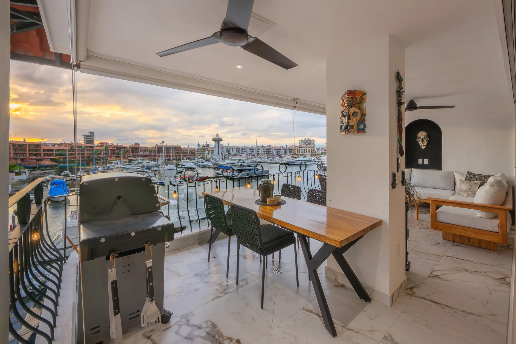 Terrace with gas grill and dining table opening off the great room at golden hour