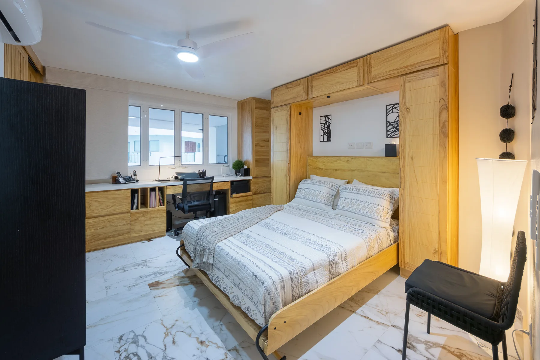 Third bedroom with the Murphy bed down, framed by floor-to-ceiling built-in wood cabinetry