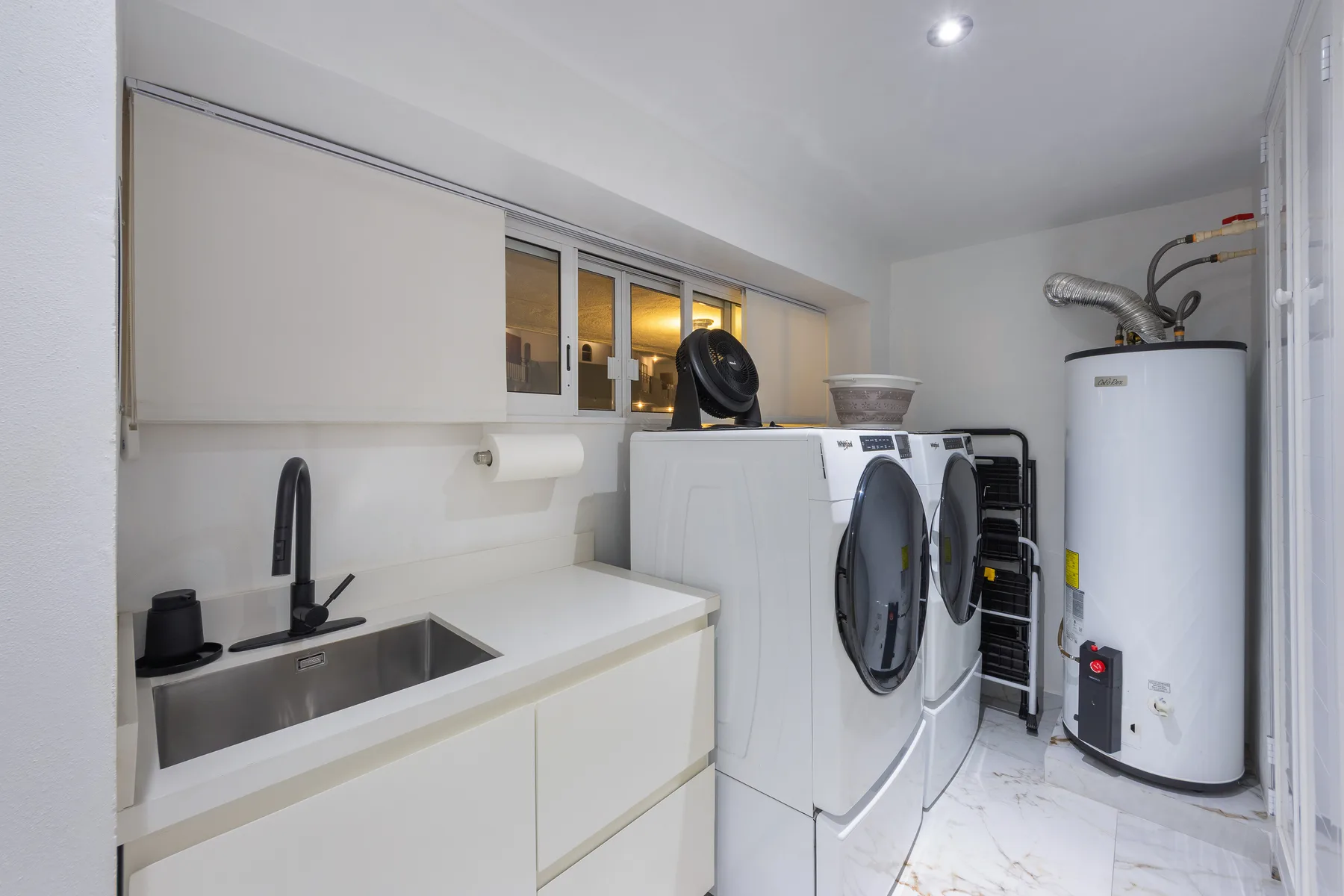Service room with full-size washer, dryer, water heater and storage cabinetry