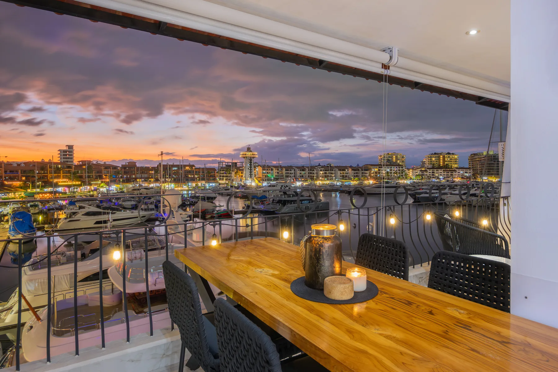 Terrace of Las Palmas 313 at dusk, dinner table set with candlelight above the Marina Vallarta boat slips